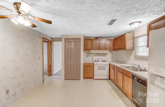 kitchen featuring under cabinet range hood, white appliances, a sink, visible vents, and brown cabinets