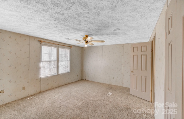 empty room featuring a textured ceiling, carpet floors, and ceiling fan