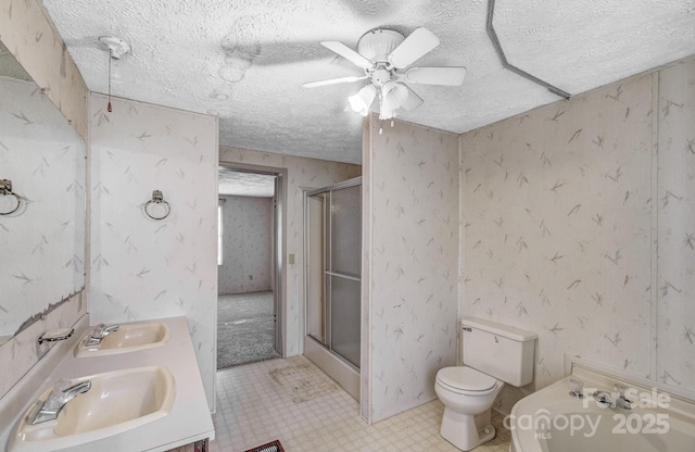 full bathroom featuring wallpapered walls, a sink, and a stall shower