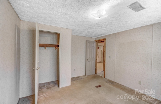 unfurnished bedroom with a closet, visible vents, a textured ceiling, and carpet flooring