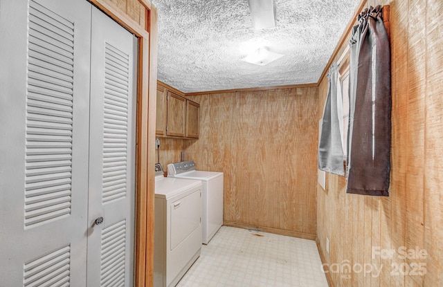 laundry room with cabinet space, light floors, washer and dryer, and wood walls