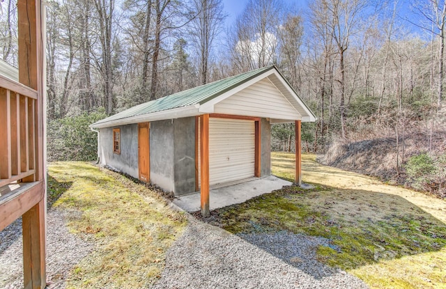 detached garage featuring driveway and a forest view