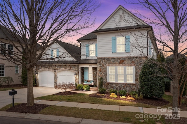 traditional home featuring a garage, stone siding, and concrete driveway