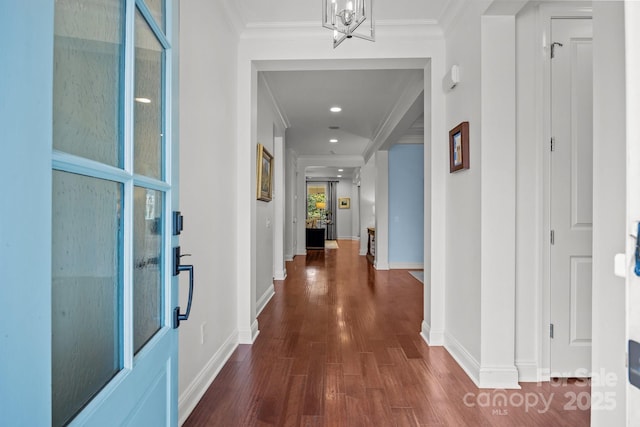 corridor featuring baseboards, an inviting chandelier, wood finished floors, and crown molding