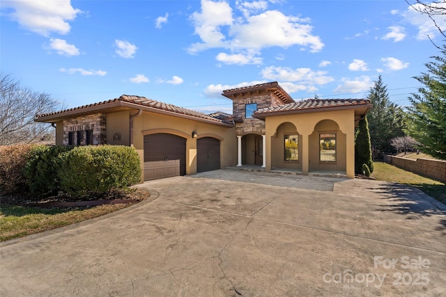 mediterranean / spanish home with a garage, stone siding, a tiled roof, and stucco siding