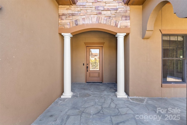 view of exterior entry featuring stone siding and stucco siding