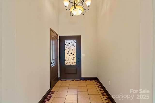 doorway to outside featuring light tile patterned floors, baseboards, and an inviting chandelier