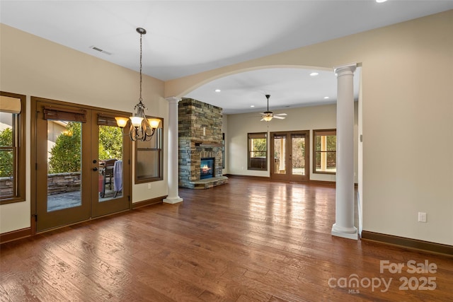 unfurnished living room with decorative columns, visible vents, wood finished floors, and french doors