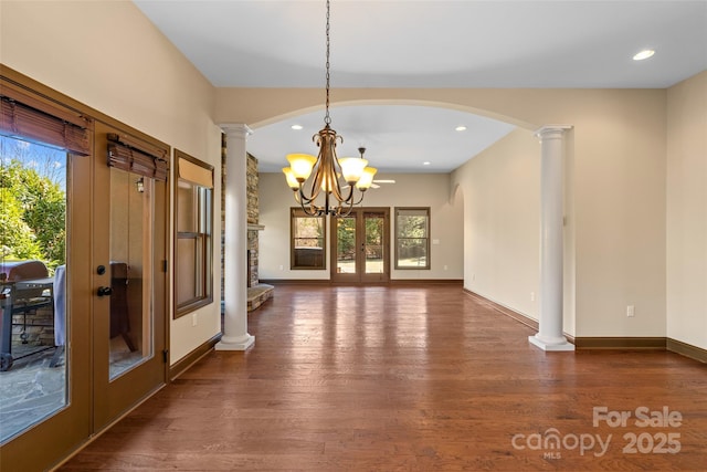 interior space featuring baseboards, french doors, wood finished floors, and ornate columns