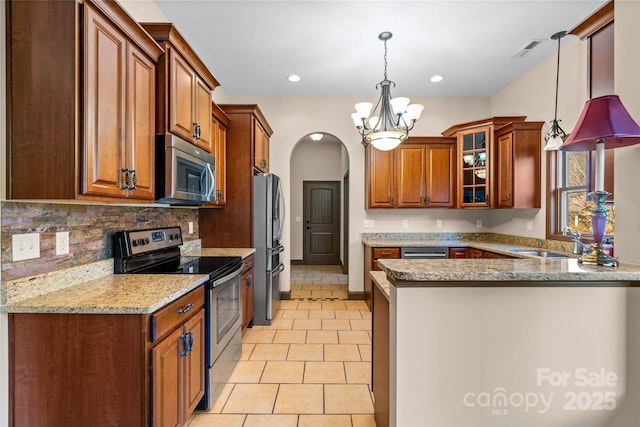 kitchen featuring visible vents, arched walkways, appliances with stainless steel finishes, brown cabinets, and a sink