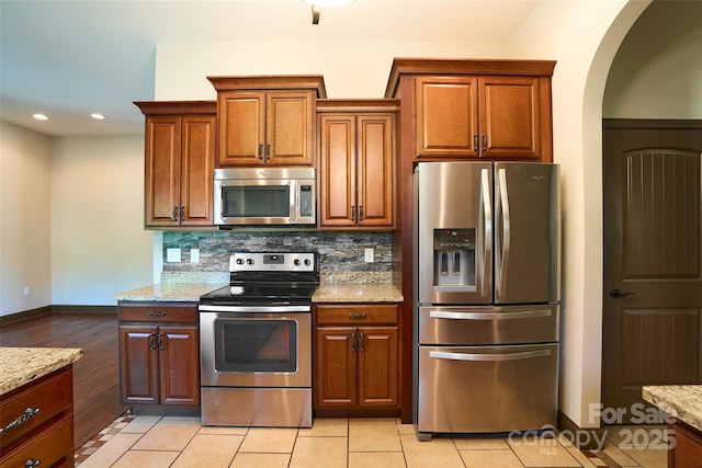 kitchen featuring light tile patterned floors, stainless steel appliances, recessed lighting, backsplash, and light stone countertops