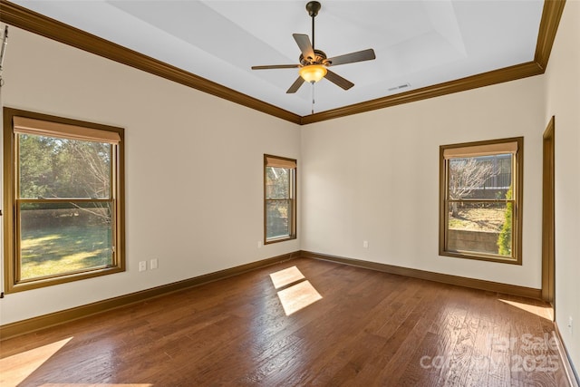 empty room featuring crown molding, wood-type flooring, visible vents, and baseboards