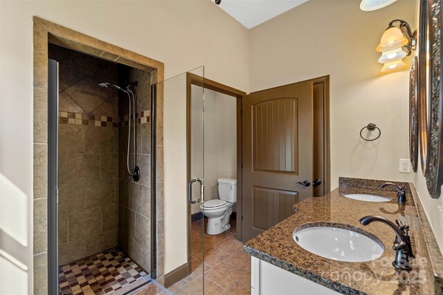 bathroom featuring double vanity, a stall shower, a sink, and tile patterned floors