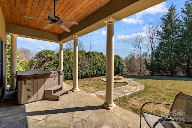 view of patio featuring a fire pit, ceiling fan, fence, and a hot tub