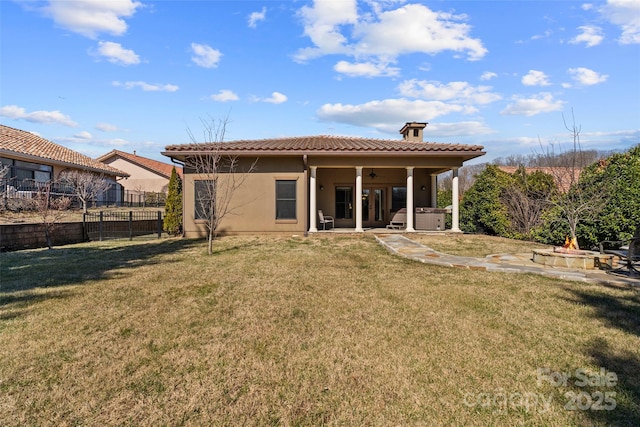 back of house with an outdoor fire pit, fence, a tiled roof, and a yard