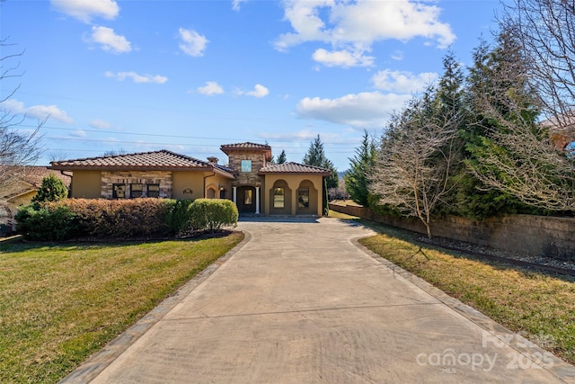 mediterranean / spanish house with driveway, a tile roof, a front yard, and stucco siding