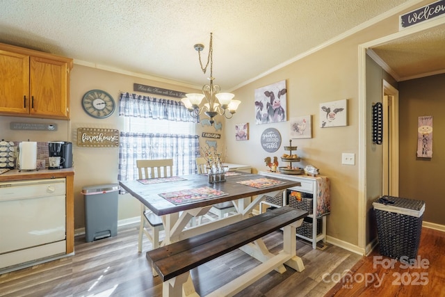 dining room with ornamental molding, a chandelier, a textured ceiling, and wood finished floors