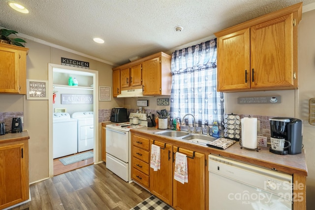 kitchen with light countertops, a sink, white appliances, independent washer and dryer, and under cabinet range hood