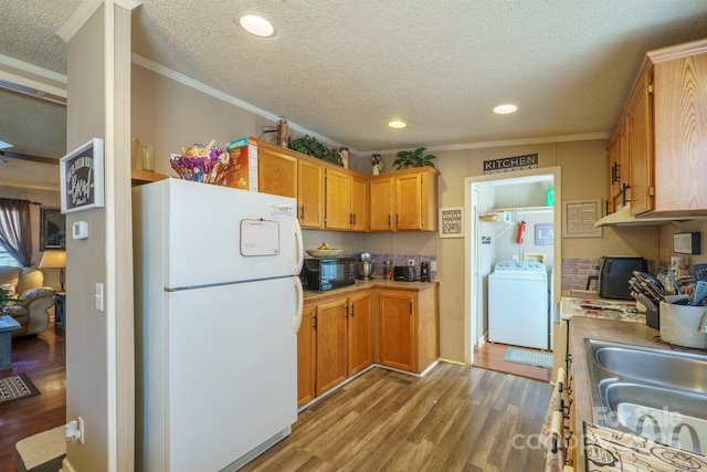 kitchen with light wood-style flooring, a sink, ornamental molding, freestanding refrigerator, and washer / clothes dryer