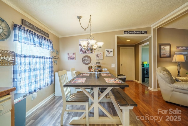 dining room with dark wood-style floors, ornamental molding, a textured ceiling, and a chandelier