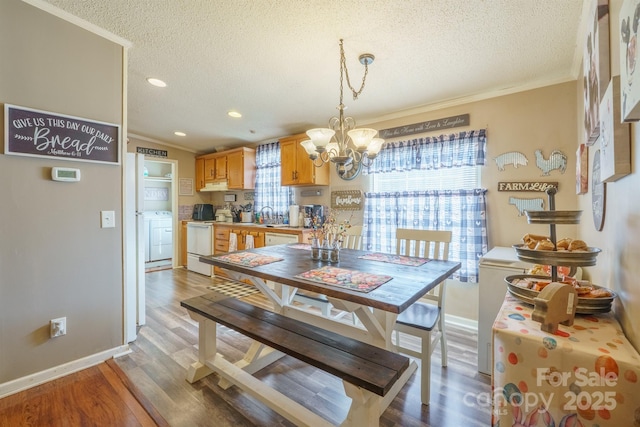 dining area featuring an inviting chandelier, a textured ceiling, light wood-style floors, and crown molding