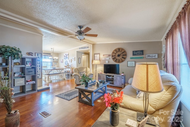 living area with ornamental molding, ceiling fan with notable chandelier, a textured ceiling, and wood finished floors