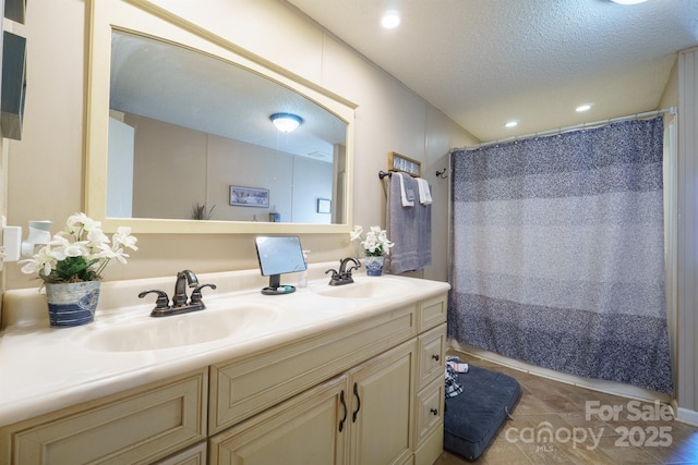 bathroom with recessed lighting, a sink, a textured ceiling, and double vanity