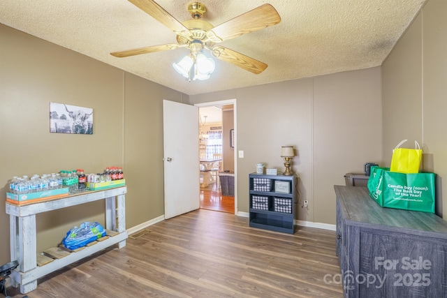 rec room with a textured ceiling, dark wood finished floors, a ceiling fan, and baseboards