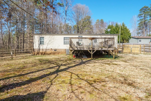 rear view of house with a fenced backyard, a lawn, and a deck