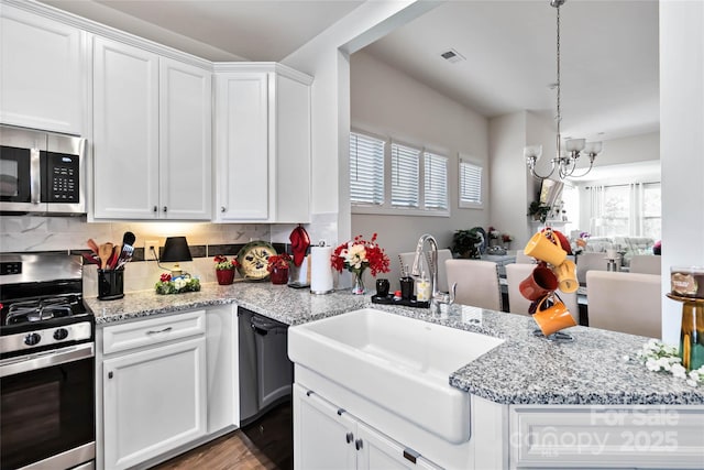 kitchen with visible vents, backsplash, appliances with stainless steel finishes, white cabinets, and a sink