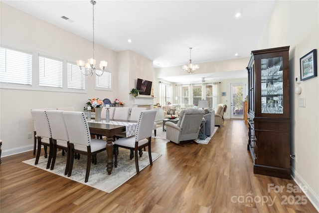 dining space with baseboards, visible vents, a chandelier, and wood finished floors