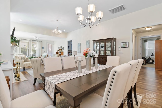 dining space with a chandelier, visible vents, and wood finished floors