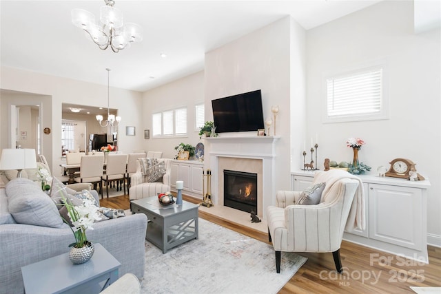 living area featuring a chandelier, a high end fireplace, and light wood finished floors