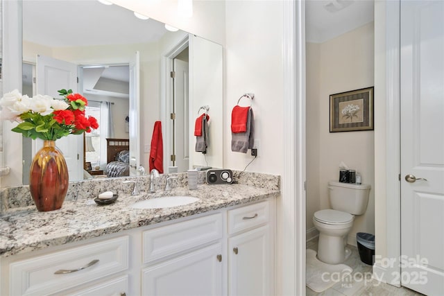 bathroom with vanity, toilet, and connected bathroom