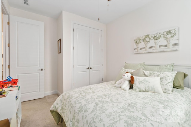 bedroom featuring a closet, visible vents, light carpet, and baseboards