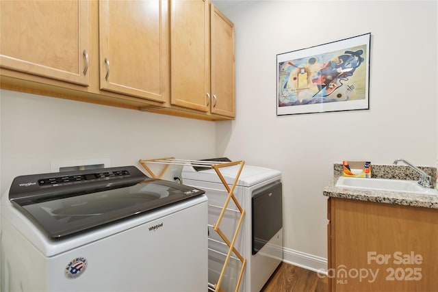 washroom with washing machine and clothes dryer, cabinet space, dark wood-type flooring, a sink, and baseboards