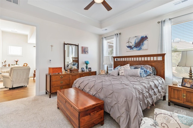 bedroom with a raised ceiling, visible vents, ornamental molding, light carpet, and baseboards