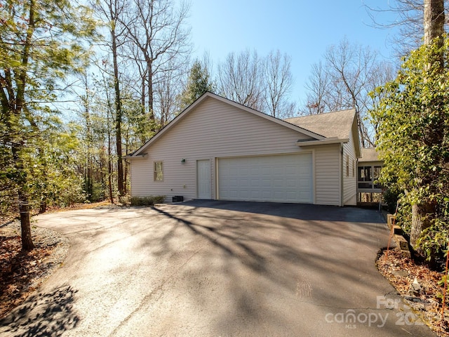 view of side of property with a garage, driveway, and a shingled roof