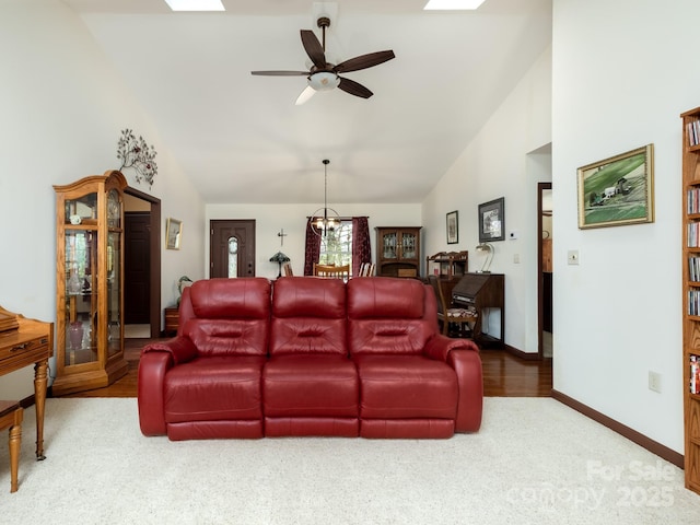 living area featuring ceiling fan, high vaulted ceiling, a skylight, carpet flooring, and baseboards