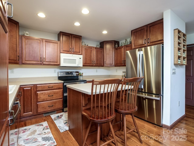 kitchen featuring stainless steel appliances, light countertops, light wood-style floors, and a kitchen bar