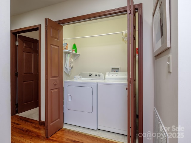 laundry room featuring light wood-type flooring, laundry area, visible vents, and independent washer and dryer