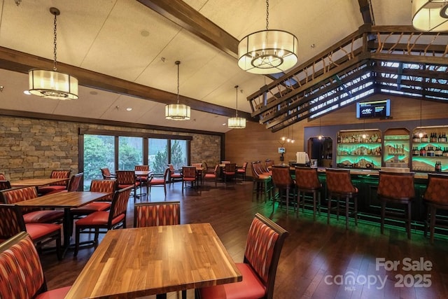 dining room featuring a community bar, beam ceiling, high vaulted ceiling, and wood-type flooring