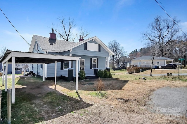 view of front of property with a carport, a shingled roof, and a chimney