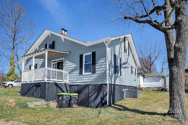 view of home's exterior with covered porch, central AC, and a lawn