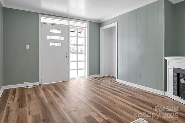 entrance foyer with crown molding, baseboards, wood finished floors, and a glass covered fireplace