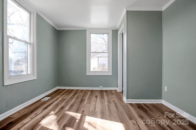 spare room featuring baseboards, crown molding, visible vents, and wood finished floors