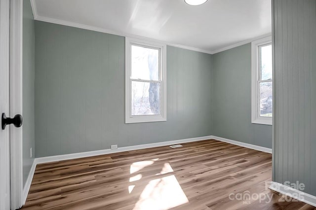 unfurnished room with baseboards, wood finished floors, and a healthy amount of sunlight