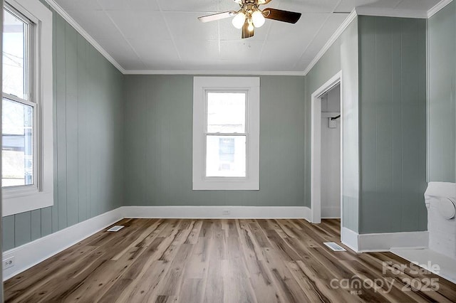 spare room with plenty of natural light, crown molding, baseboards, and wood finished floors