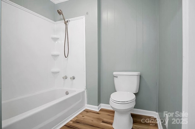 bathroom with tub / shower combination, wood finished floors, toilet, and baseboards