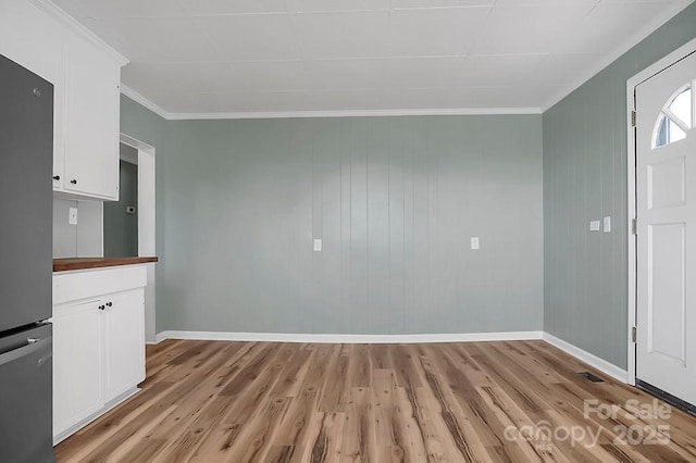 interior space featuring light wood-style floors, baseboards, and crown molding